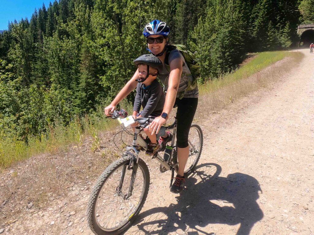 mom riding a bike on a mountain trail with her son sitting on a front-mounted bike seat