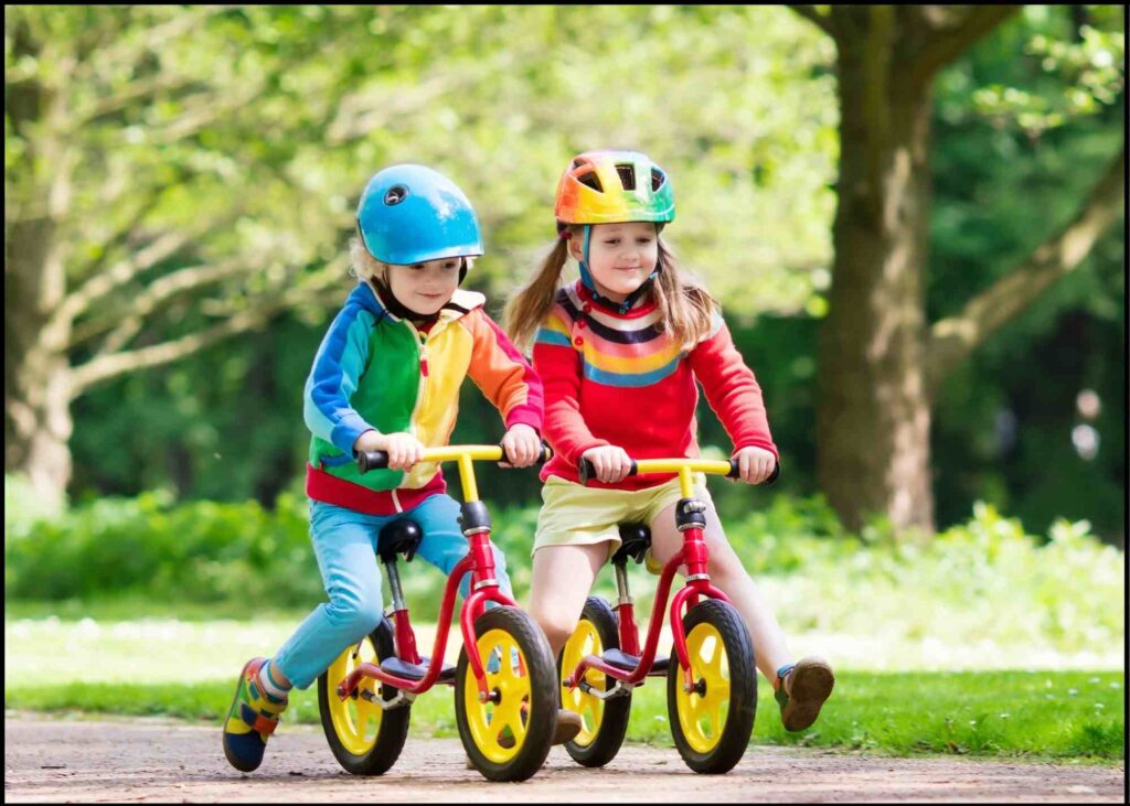 2 kids with biking gears riding balance bikes. balance bikes vs training wheels