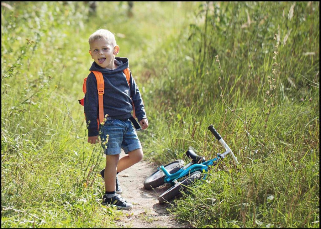 smiling kid with a backpack trail riding with a balance bike for older kids